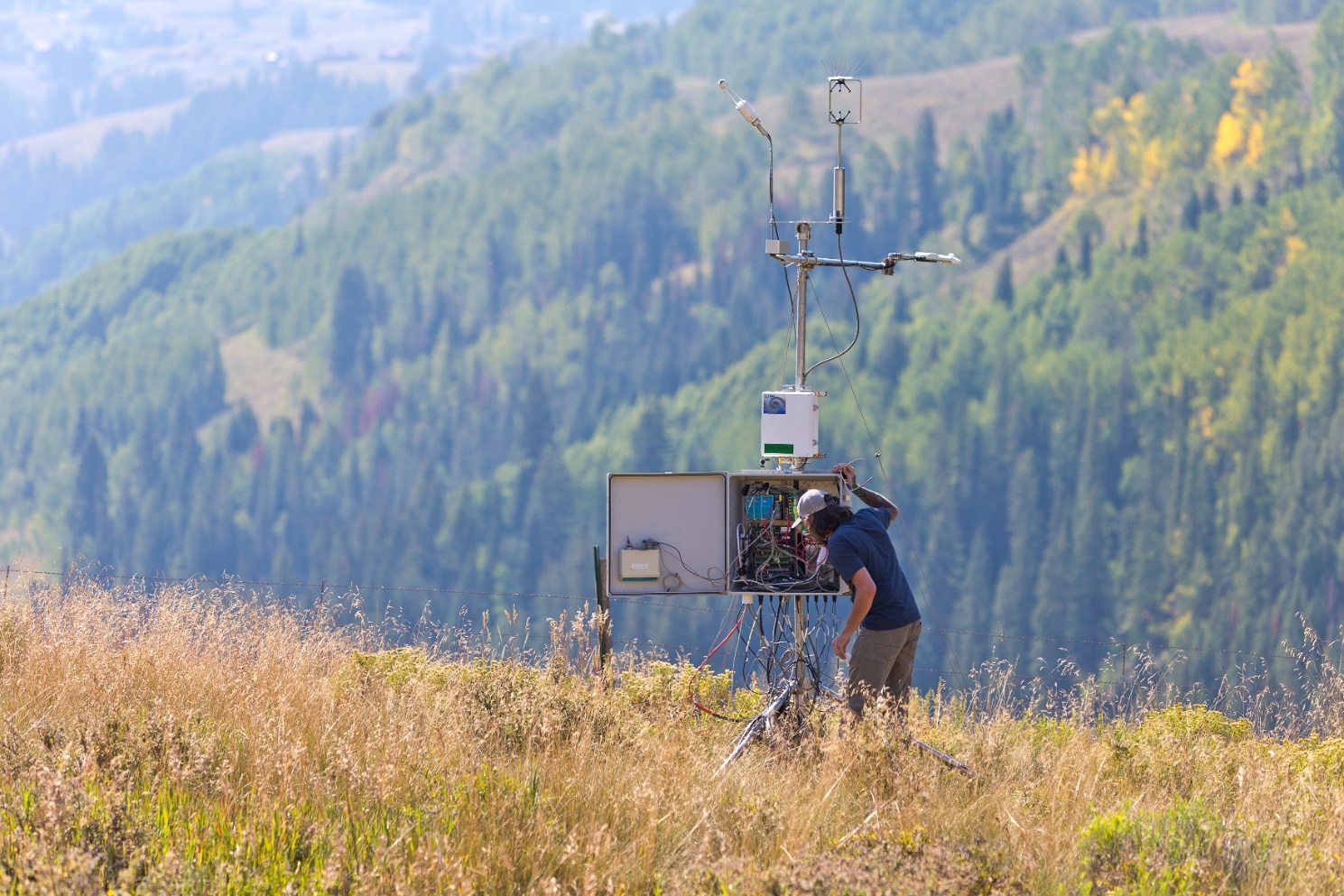 Wessley King peers inside an instrument box on a hillside.